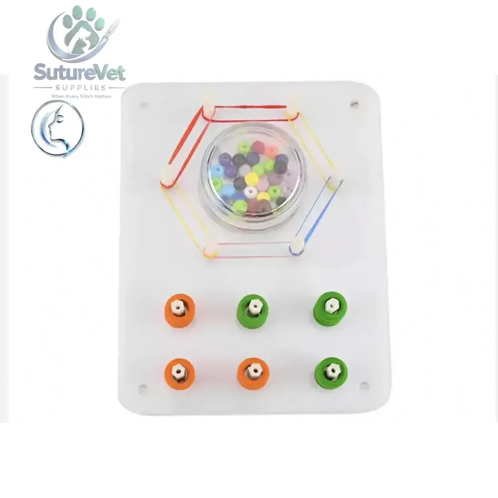 White plastic laparoscopic training module with peg transfer board featuring colorful beads, elastic bands, and colored pegs