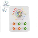 White plastic laparoscopic training module with peg transfer board featuring colorful beads, elastic bands, and colored pegs